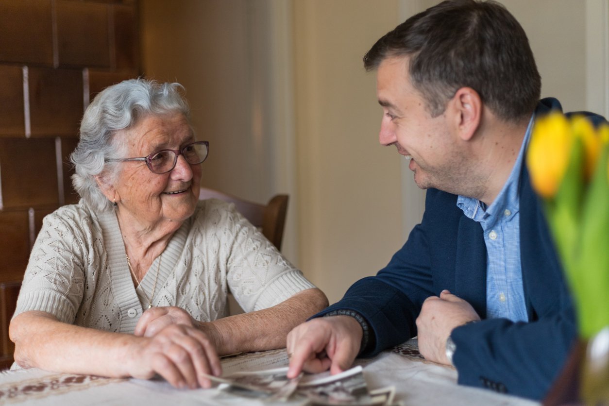 An elderly woman and a middle-aged man are sitting at a table